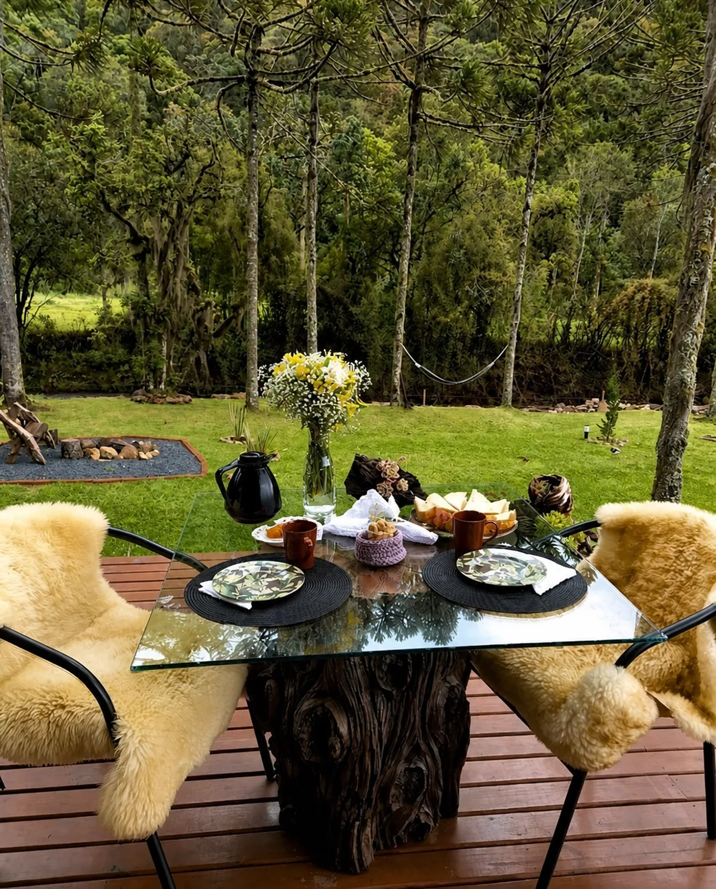 Mesa de café da manhã para duas pessoas no deck da Cabana Araucária diante da mata