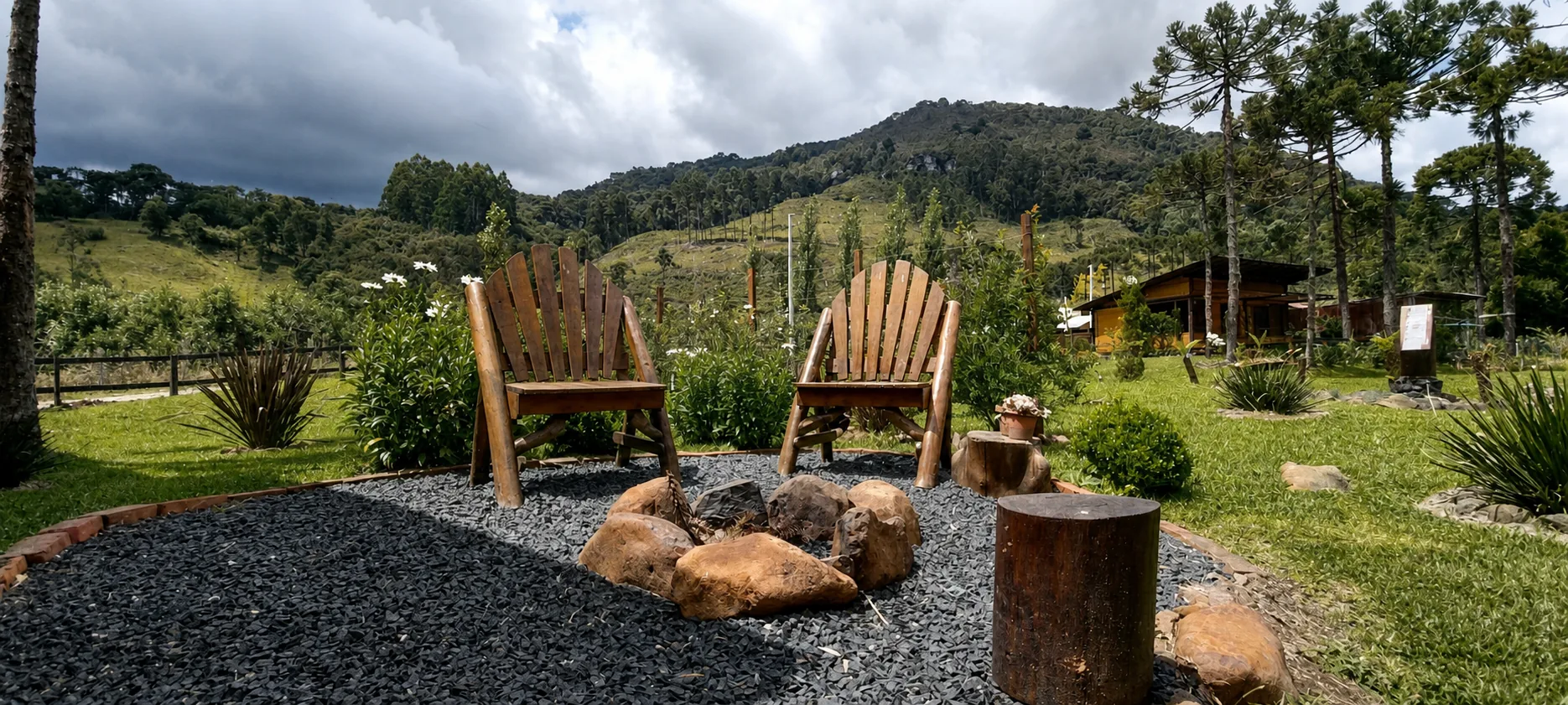 Cadeiras junto à fogueira diante do jardim e das montanhas da Cabana do Rio