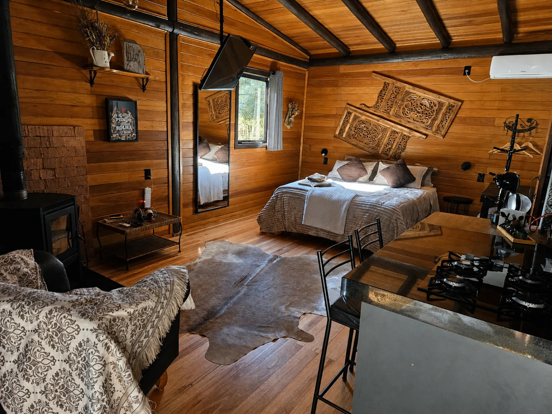 Interior da Cabana do Rio com cama, cozinha, sofá e lareira