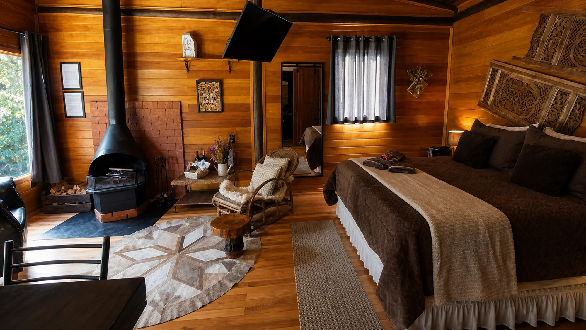 Quarto amplo em madeira da Cabana do Rio com cama e lareira