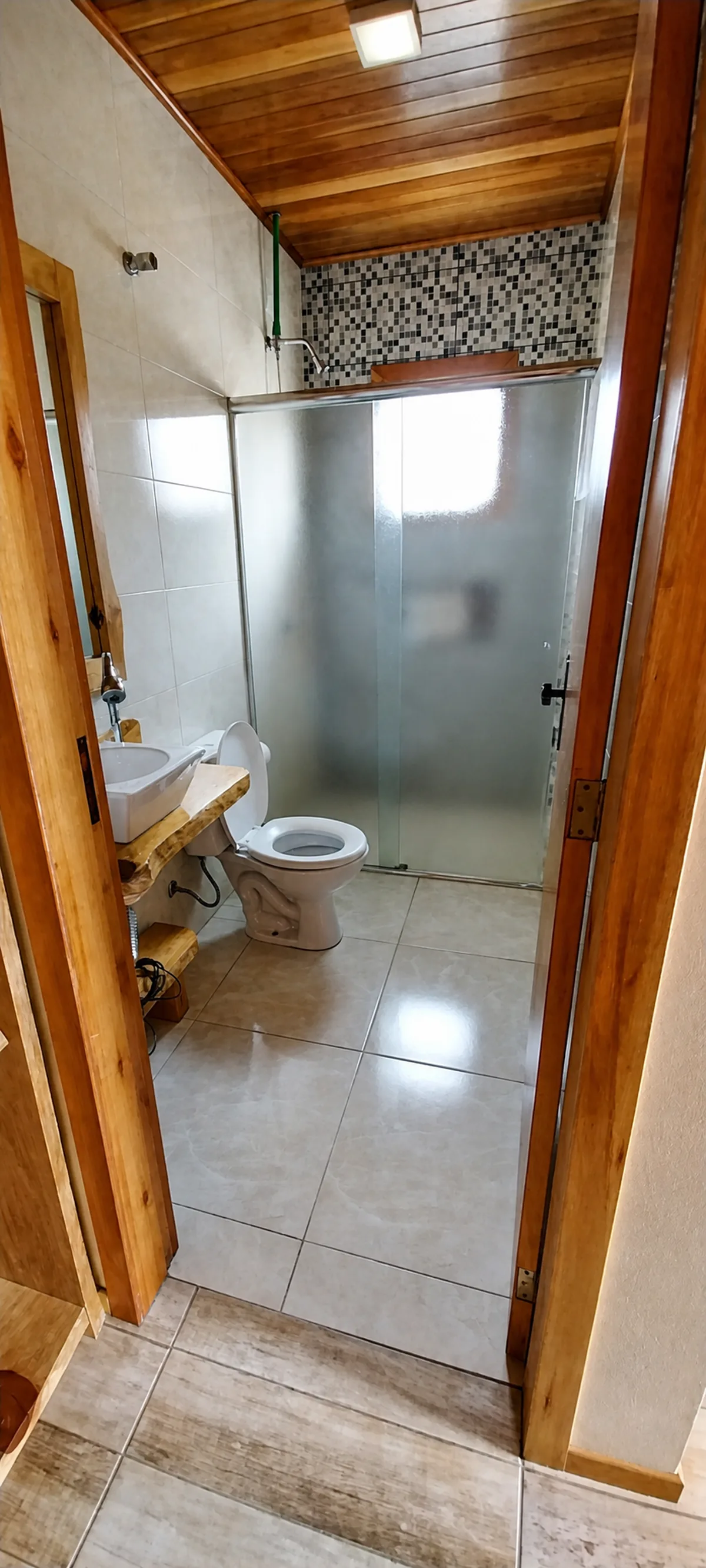 Banheiro privativo de um chalé da Pousada Sentiero com box e acabamento em madeira