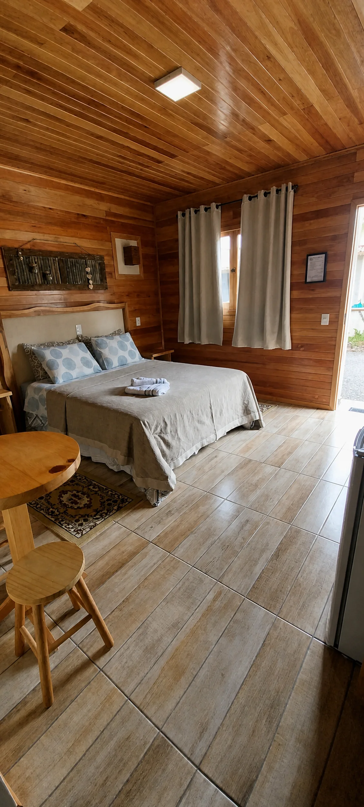 Quarto amplo da Pousada Sentiero com cama de casal, mesa e banco de madeira
